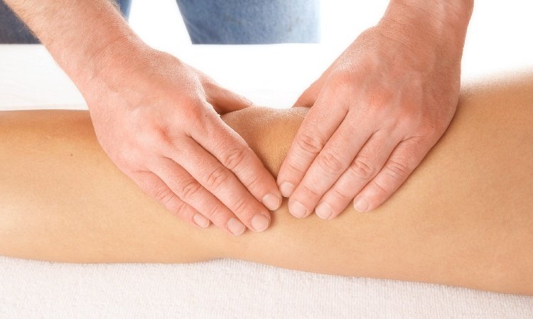Nahaufnahme von zwei Händen einer Person, die das Knie einer anderen anfässt